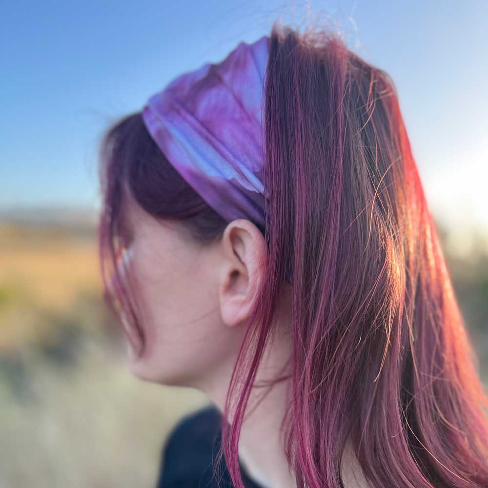 Stretch headband sideview worn by a young woman. Almost Magenta peony flower.  
