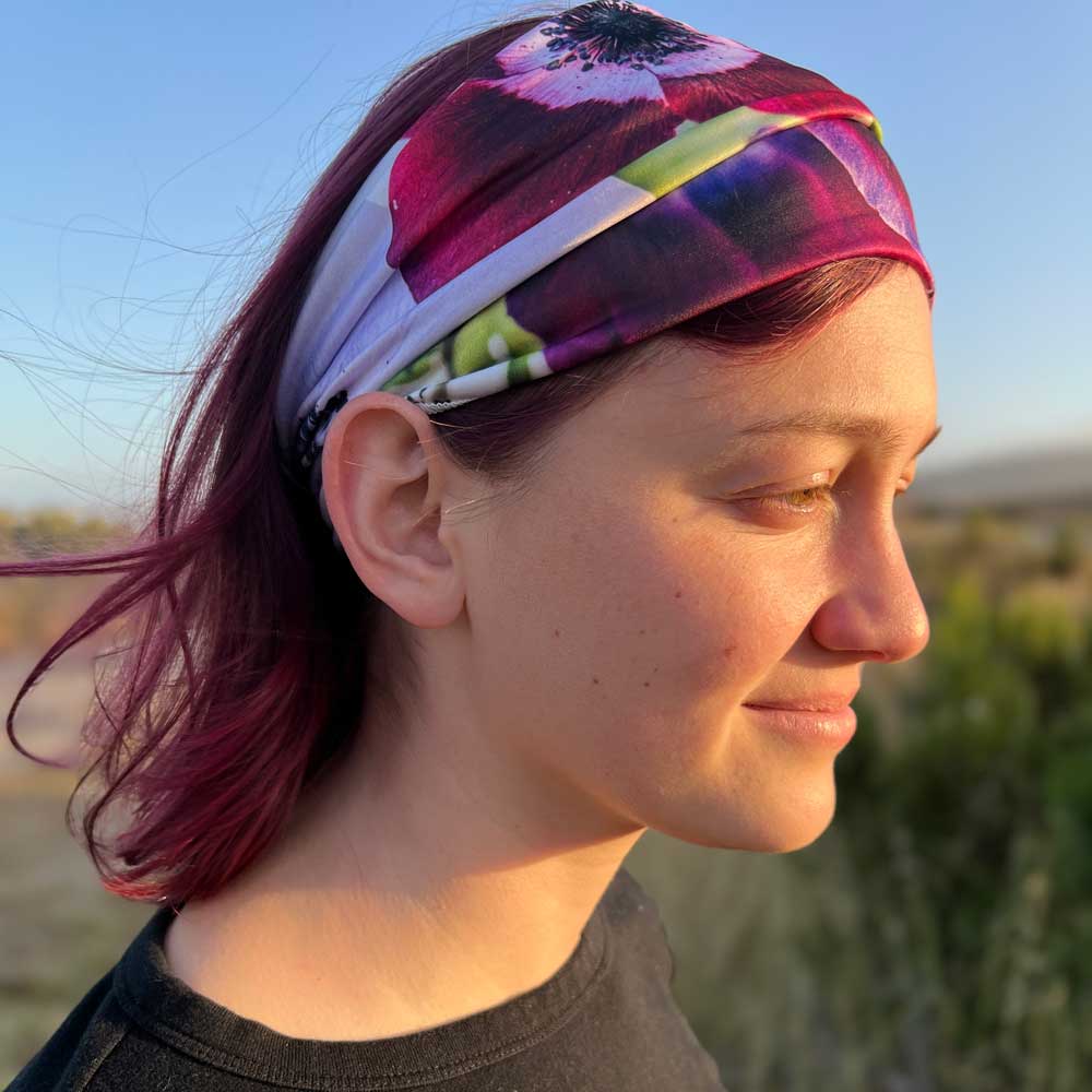 Stretch floral headband sideview worn by a young woman; vibrant purple and magenta flowers shown.