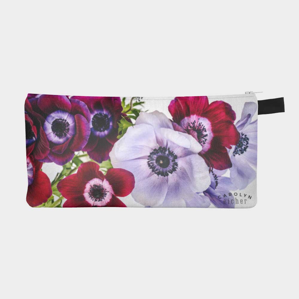 Close-up of zippered pouch with vibrant bouquet of anemone flowers in purple and red, front view.