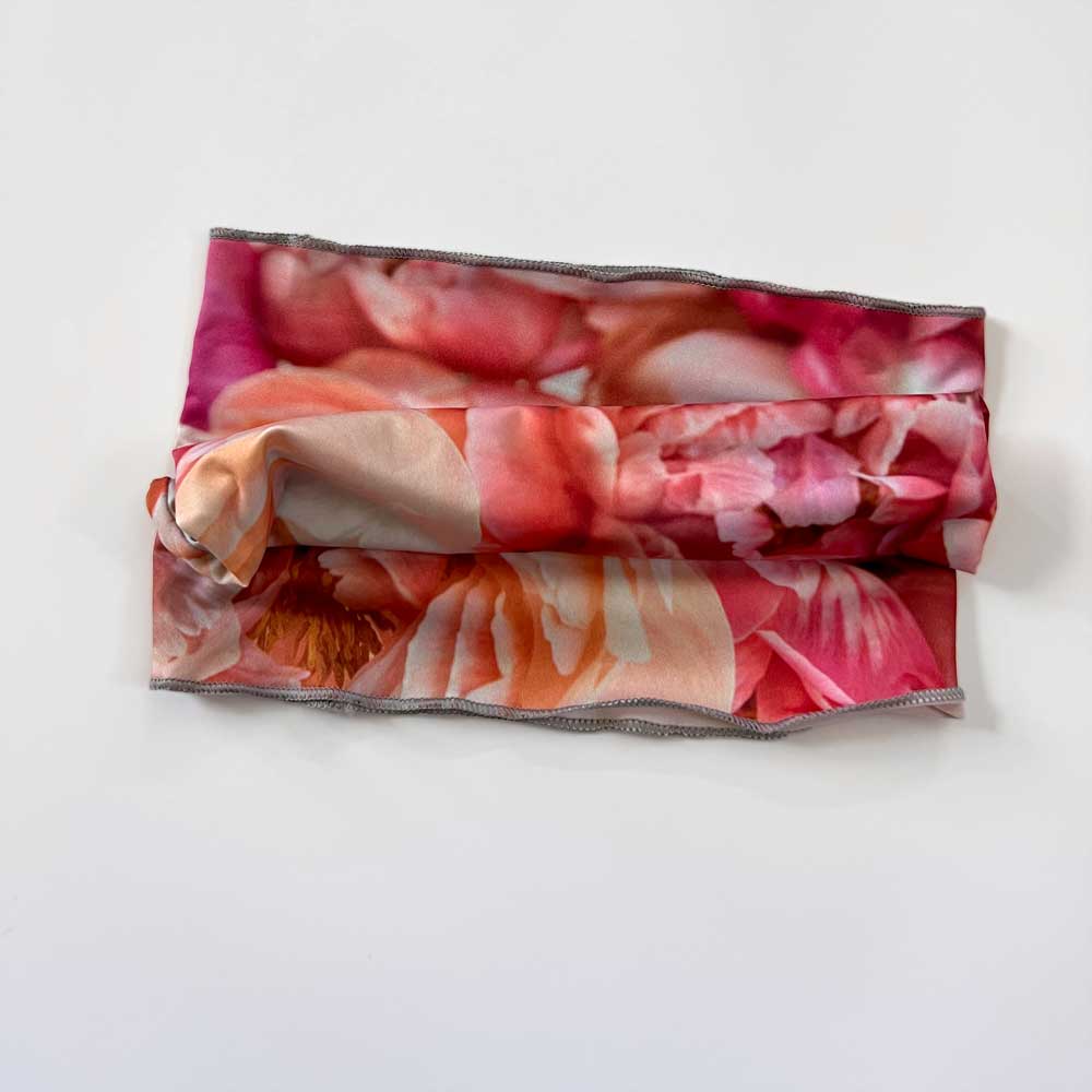Folded view of peach floral stretch headband against a white background.