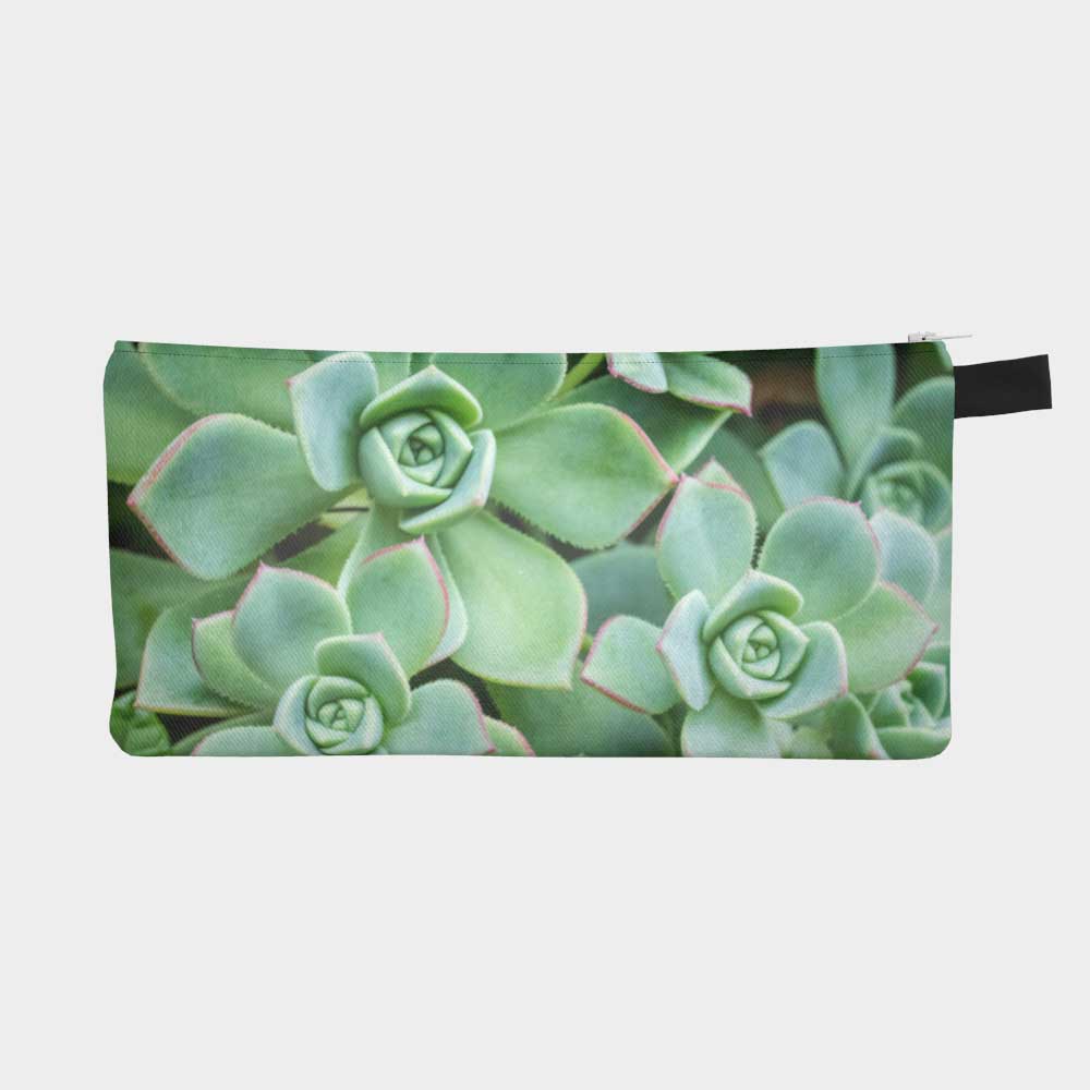 Close-up of zippered pouch with bright green succulents with red edges. 