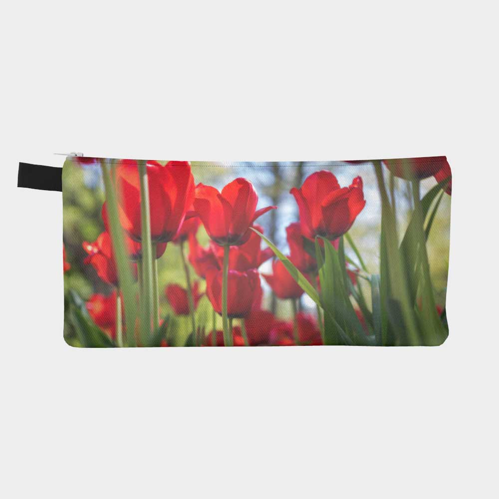 Close-up of back of zippered pouch showing bright red tulips bursting up from the ground with vibrant green stems.