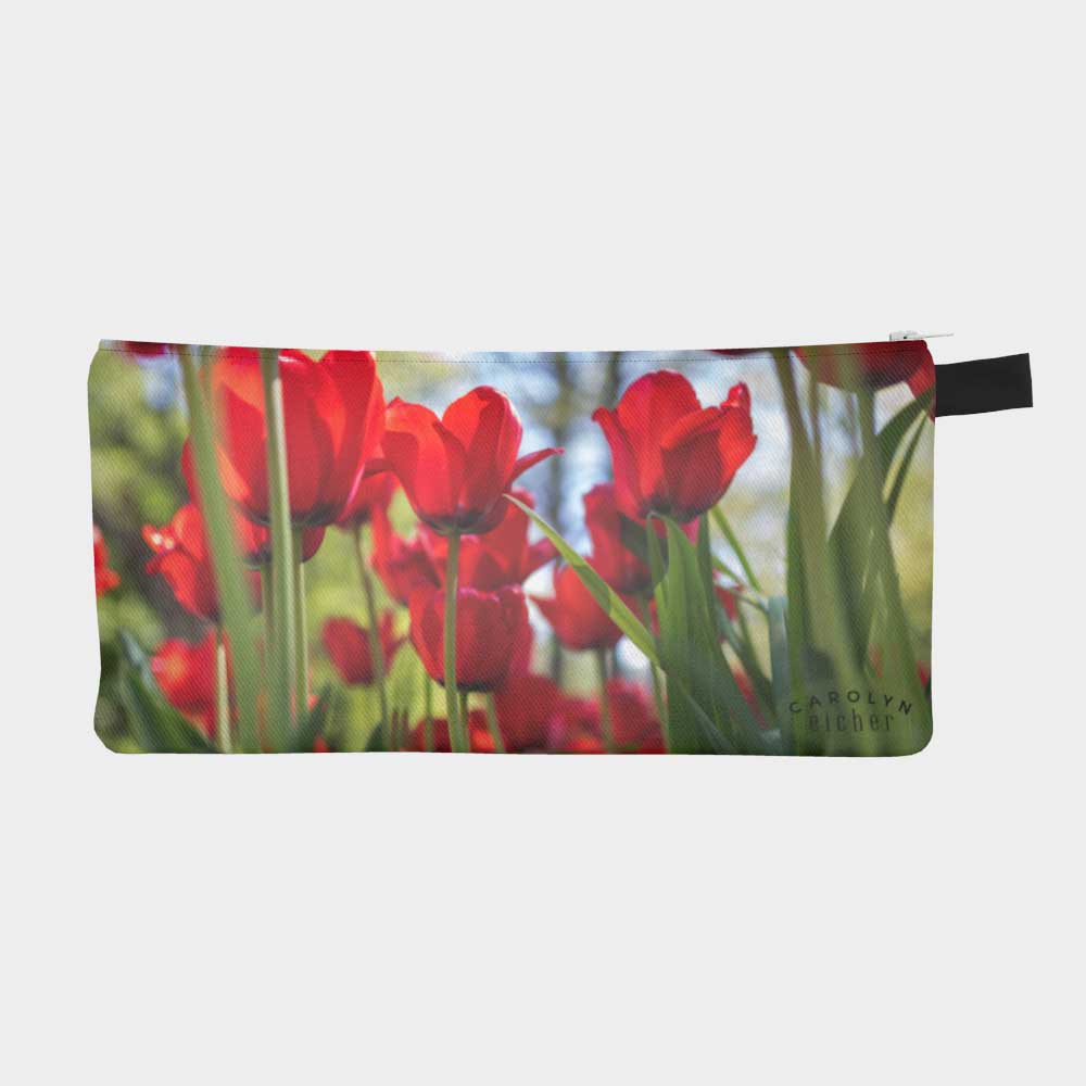 Close-up of zippered pouch with vibrant red tulips bursting towards the blue sky.